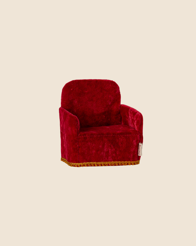 The Maileg Soft Chair - Red, available for pre-order and shipping late February, features a small plush design with a soft textured surface and decorative golden trim on a plain beige background, making it ideal for charming mouse hole farmhouse settings.