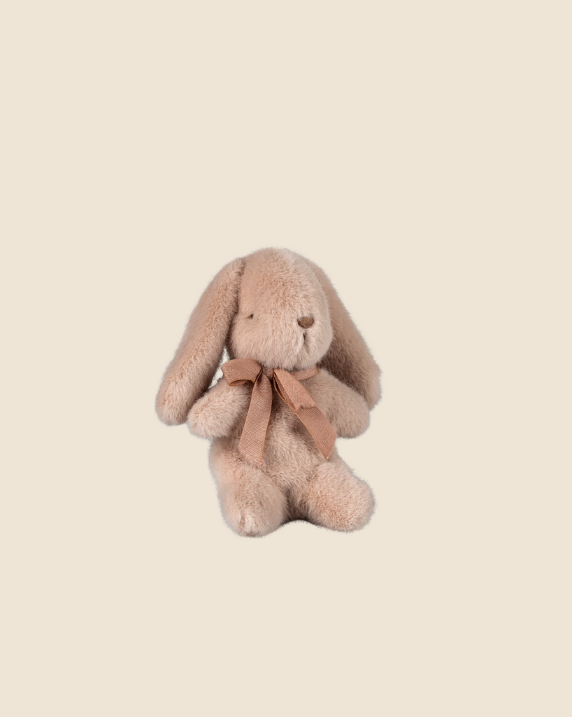 A soft, sweet-looking plush bunny with droopy ears and a brown ribbon sits against a beige background, made from recycled polyester. Available for pre-order: Maileg Plush Bunny - Light Powder (ships late February).