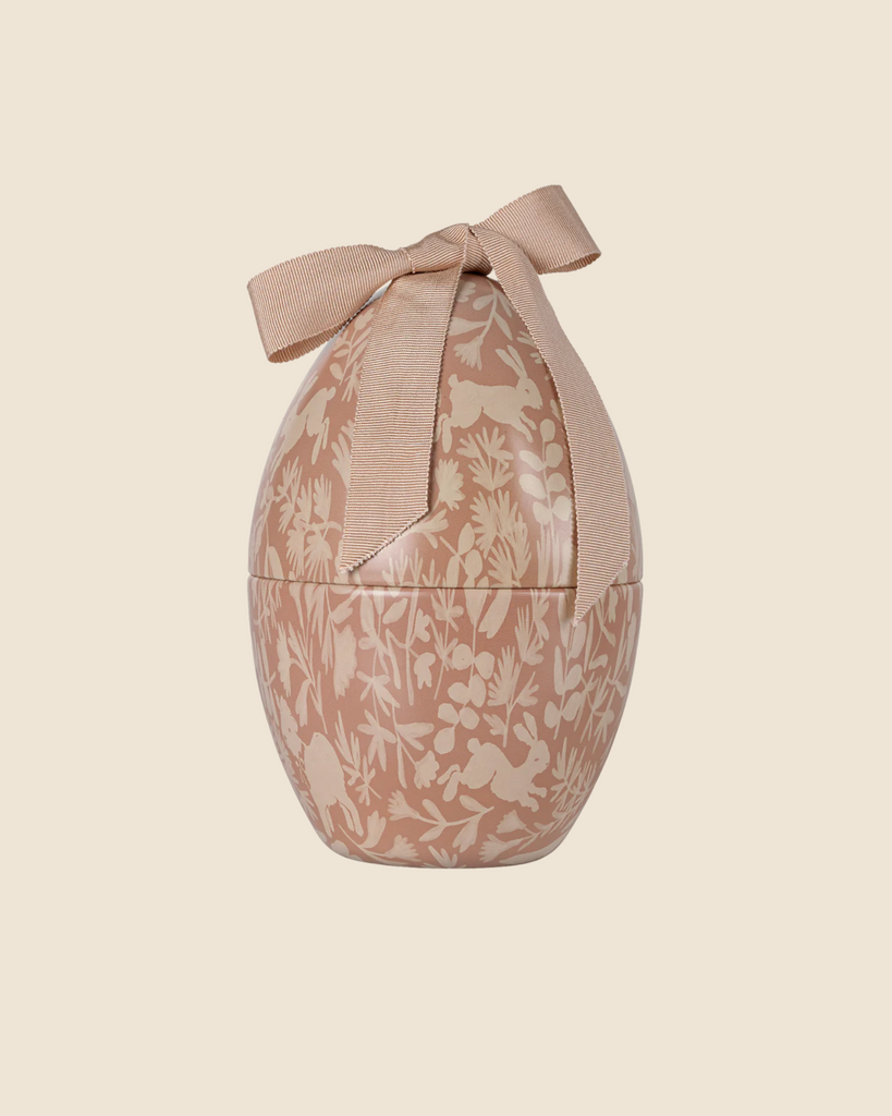 The PRE-ORDER: Maileg Easter Egg - Powder is a decorative metal container adorned with a floral pattern and large bow. Its light brown and cream shades provide an exclusive look, adding elegance against a pale background. Ships in February.