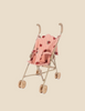 The Konges Sloejd Doll Stroller - Ladybug is a lightweight pink umbrella stroller with a playful ladybug pattern, designed for extra stability. It includes curved handles and four small wheels, all set against a solid beige background.