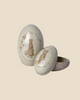 A set of two Maileg Easter Eggs, featuring metal construction with rabbit and flower illustrations. One egg is open, displaying a Dorthe Mailil embroidery-inspired pattern inside. These charming decorative pieces ship in approximately one week.