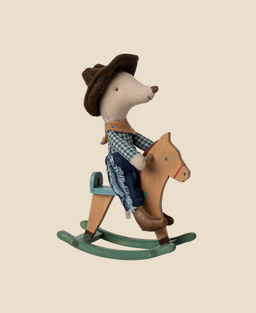 The Maileg Cowboy Mouse On Rocking Horse, Little Brother, features a cute mouse in a hat, plaid shirt, and jeans riding a green rocking horse—an adorable play set. Ships in one week.