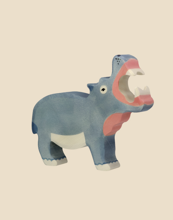 The Holztiger Hippo, handcrafted from wood, features an open mouth displaying white teeth and a pink tongue. This blue figure is set against a plain beige background. Ships in one week.