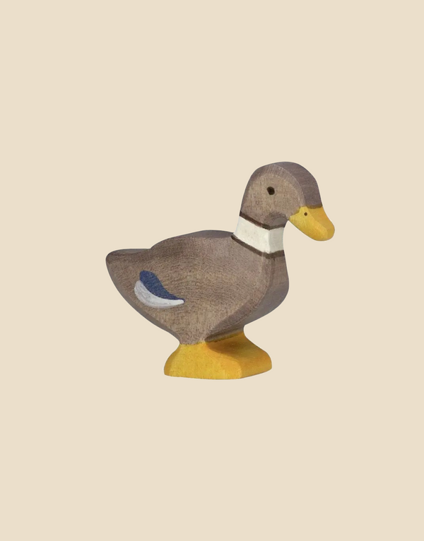 The Holztiger Duck, Standing is a handcrafted figurine made from maple and beech wood, featuring painted yellow feet and beak, a white neck ring, and a blue wing patch. It is displayed against a plain light beige background.