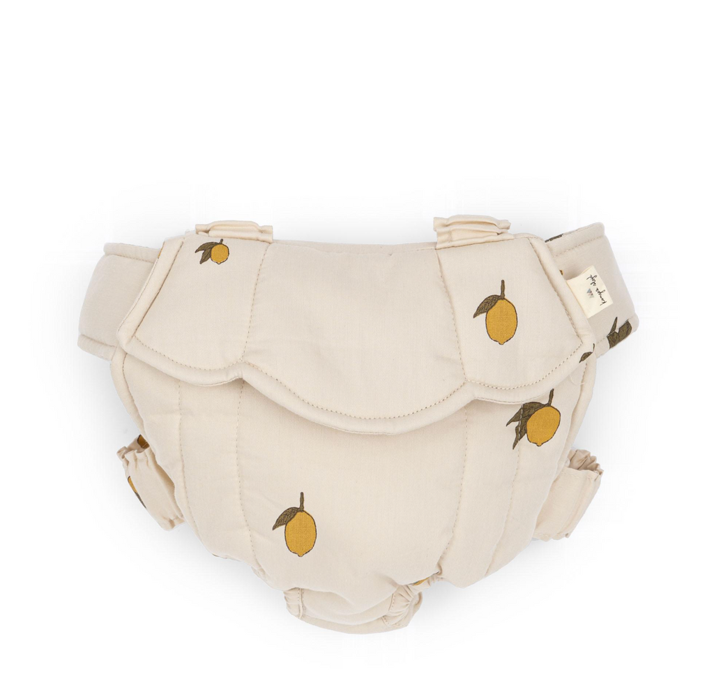 The Konges Sloejd Doll Carrier - Lemon features quilted, cream-colored cotton with a lemon pattern and adjustable straps, shown against a white background.