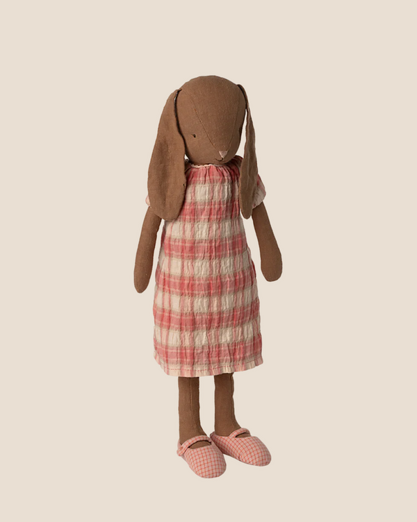 The Maileg Bunny, Size 3 in chocolate brown, wears a pink and white plaid dress with matching shoes and stands upright against a plain beige background.
