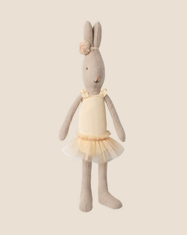 The Maileg Rabbit, Size 1 - Classic, wears a cream ballet suit and skirt, accented with a flower headband. Standing upright on a beige background, it looks like a little ballet dancer.