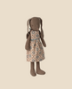 The Maileg Bunny, Size 2 - Brown - Dress, featuring floppy ears and a beige floral dress with blue and brown flowers, stands upright against a plain light beige background.