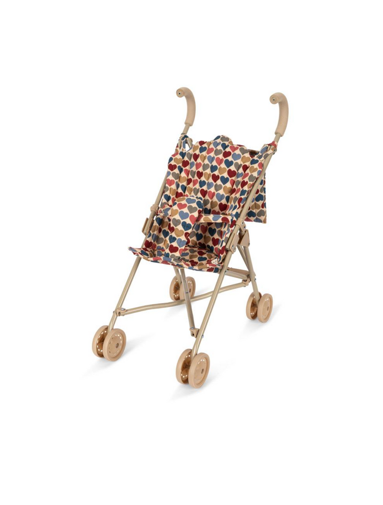 The Konges Sloejd Doll Stroller - Heart Kisses is a lightweight stroller with a beige frame, double wheels, and a fabric seat decorated in a colorful heart pattern.