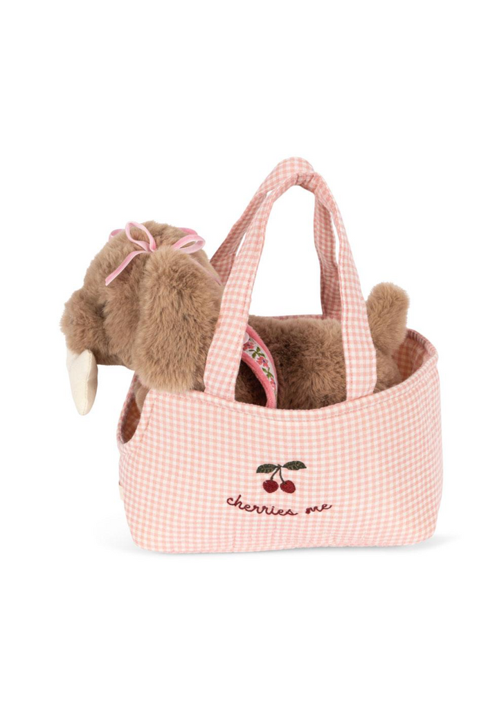 The Konges Sloejd Maude Puppy in Basket is a soft toy with a pink bow, nestled in a pink gingham tote embroidered with cherries and “cherrie me.”.