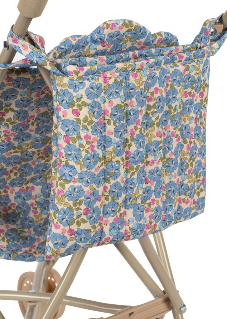 A close-up of the Konges Sloejd Doll Stroller - Rose Flower shows a removable storage bag with blue and pink flowers and green leaves on white, attached to a beige metal frame.