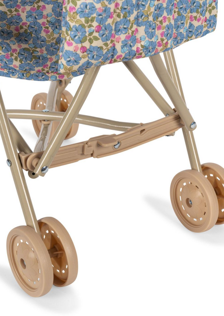 The Konges Sloejd Doll Stroller - Rose Flower features tan plastic wheels and frame, double wheels, and a seat with blue and pink floral fabric, shown against a white background.