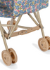 The Konges Sloejd Doll Stroller - Rose Flower features tan plastic wheels and frame, double wheels, and a seat with blue and pink floral fabric, shown against a white background.