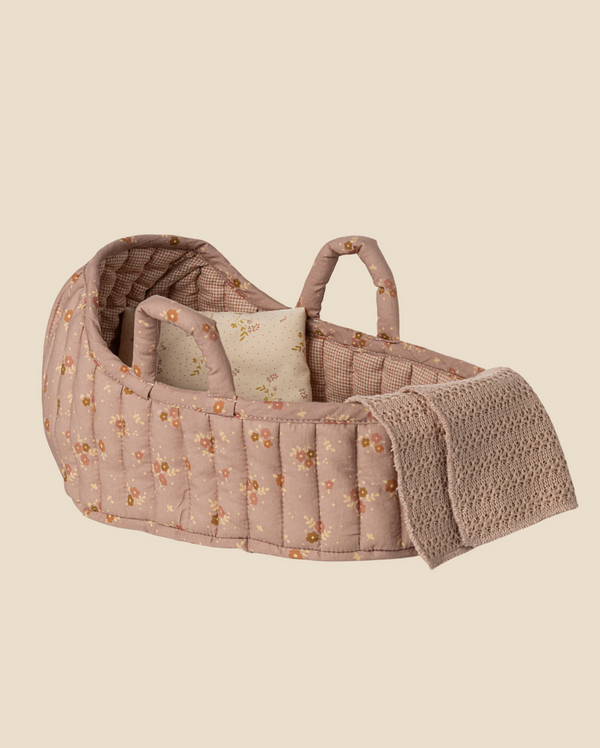 The Maileg Carry Cot, Large - Rose is a soft, quilted bassinet with floral pattern, two handles, a matching pillow, and a beige knit blanket—ideal as doll bedding or a portable carry cot, shown on a plain light background.
