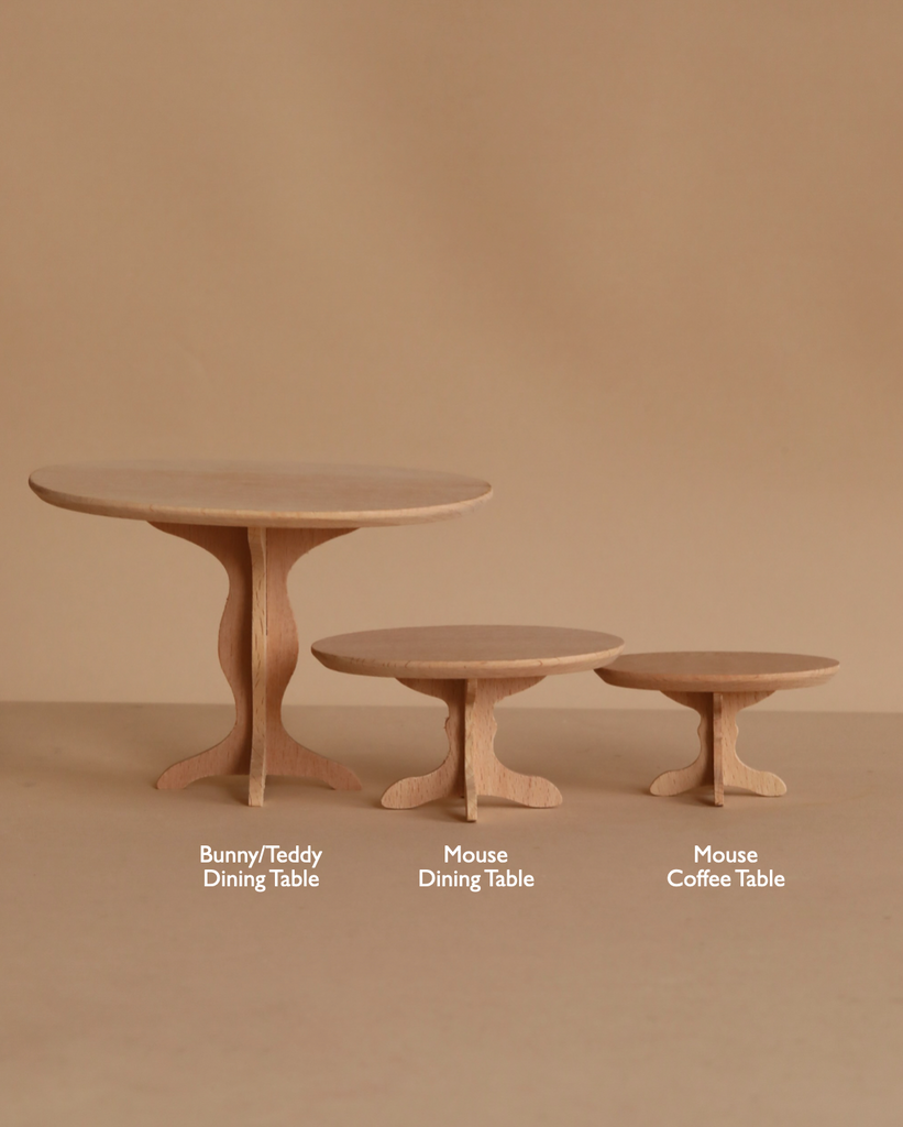 A Maileg Oval Dining Table, Mouse Size in a natural wood finish is displayed against a beige background.