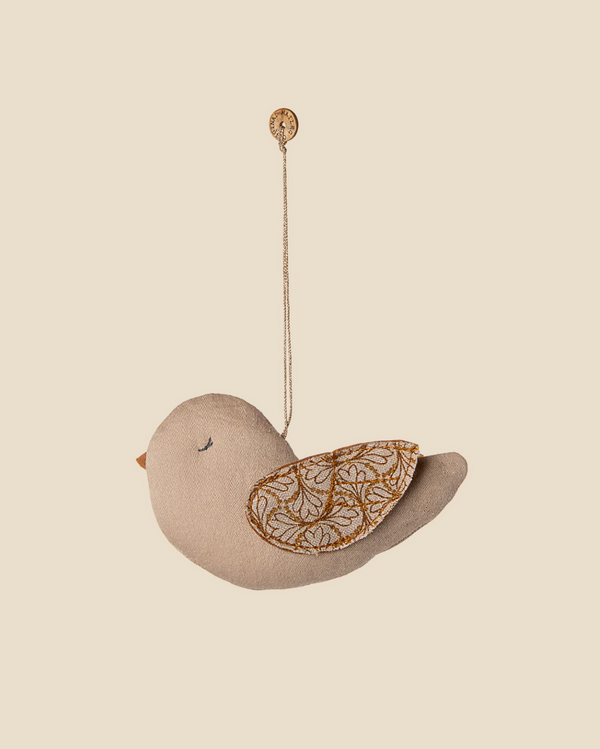 The Maileg Fabric Ornament, Bird - Winter Heart - Sand is a soft, beige bird with an embroidered brown and gold wing, hanging by a string—a charming accent for your wall or as a distinctive Christmas tree ornament.