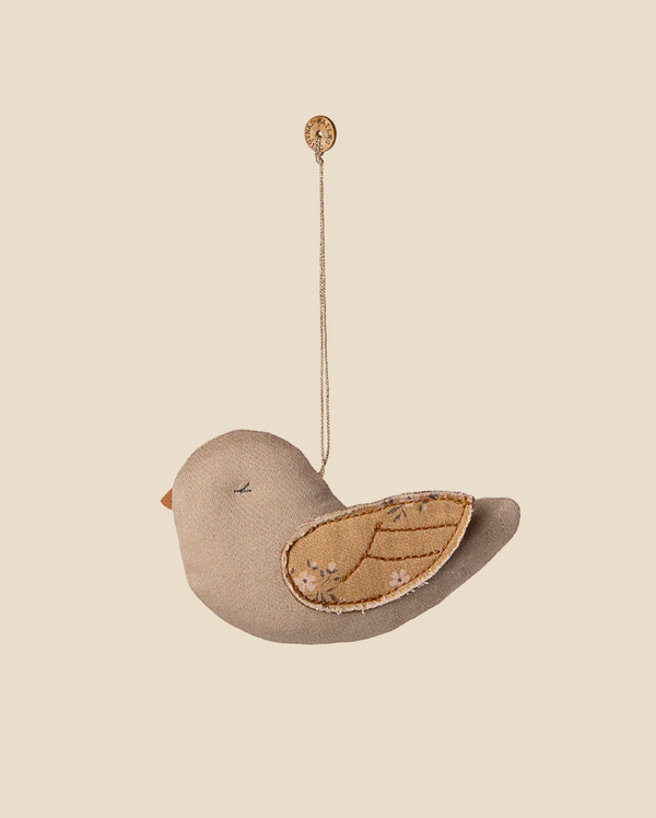 The Maileg Fabric Ornament, Bird - Mable - Latte features soft fabric, stitched details, and patterned wings, hanging from a string with a button—an adorable decoration for your Christmas tree.