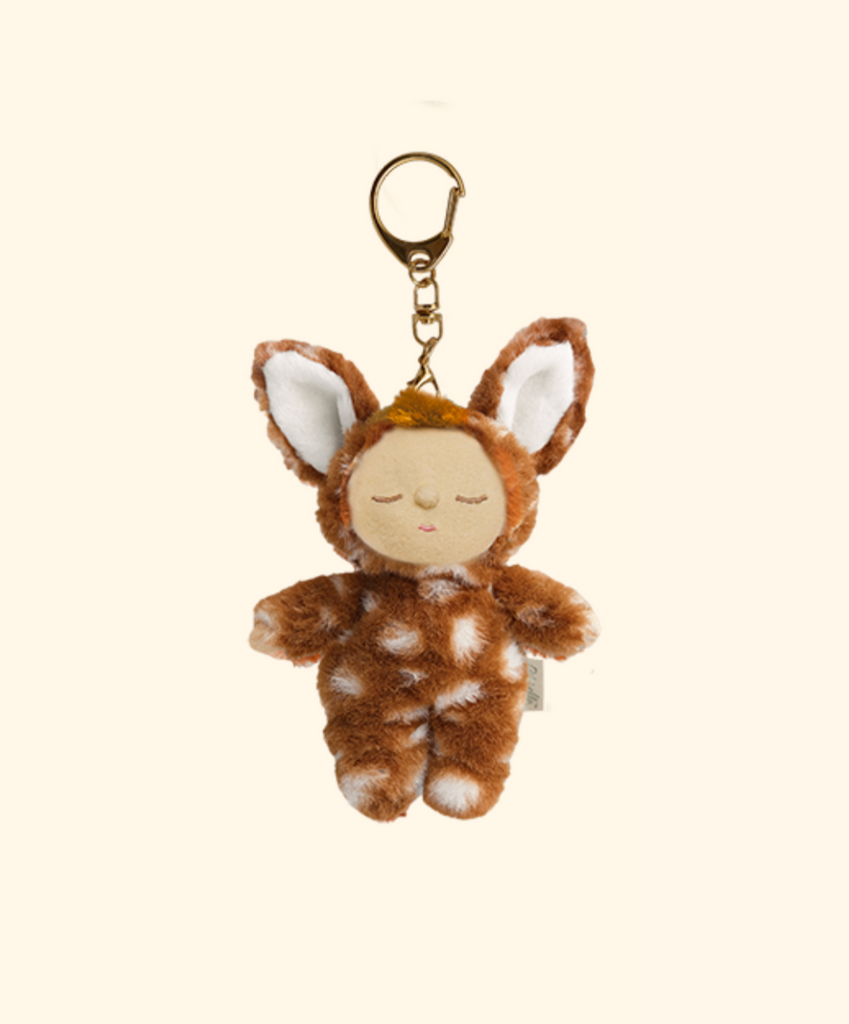 The Olli Ella Cozy Bag Charm - Fawny Lala features a small plush doll in a brown and white spotted deer costume with closed eyes and large ears, attached to a gold keyring.