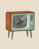 The Maileg Television, Mouse (arriving 03/15/26) is a retro wooden toy TV with angled legs and a turquoise frame, featuring cowboy and desert artwork—a charming addition to any dollhouse decor.