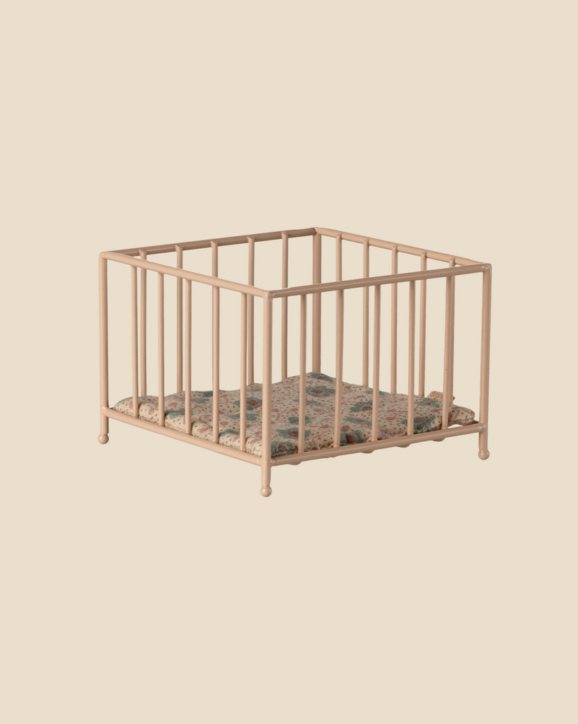 The Maileg Nursery Set with Brothers and Sisters features a small beige metal square playpen with vertical bars and a patterned cushion, ideal as a matchbox bed or for Maileg mice, shown against a plain light beige background.