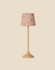 Pre-order the Maileg Floor Lamp, Miniature - Dark Powder (arrives by 03/15/26), featuring a pink base and a floral-patterned shade with yellow and red flowers—an ideal, charming accessory for any dollhouse. Set against a beige background.