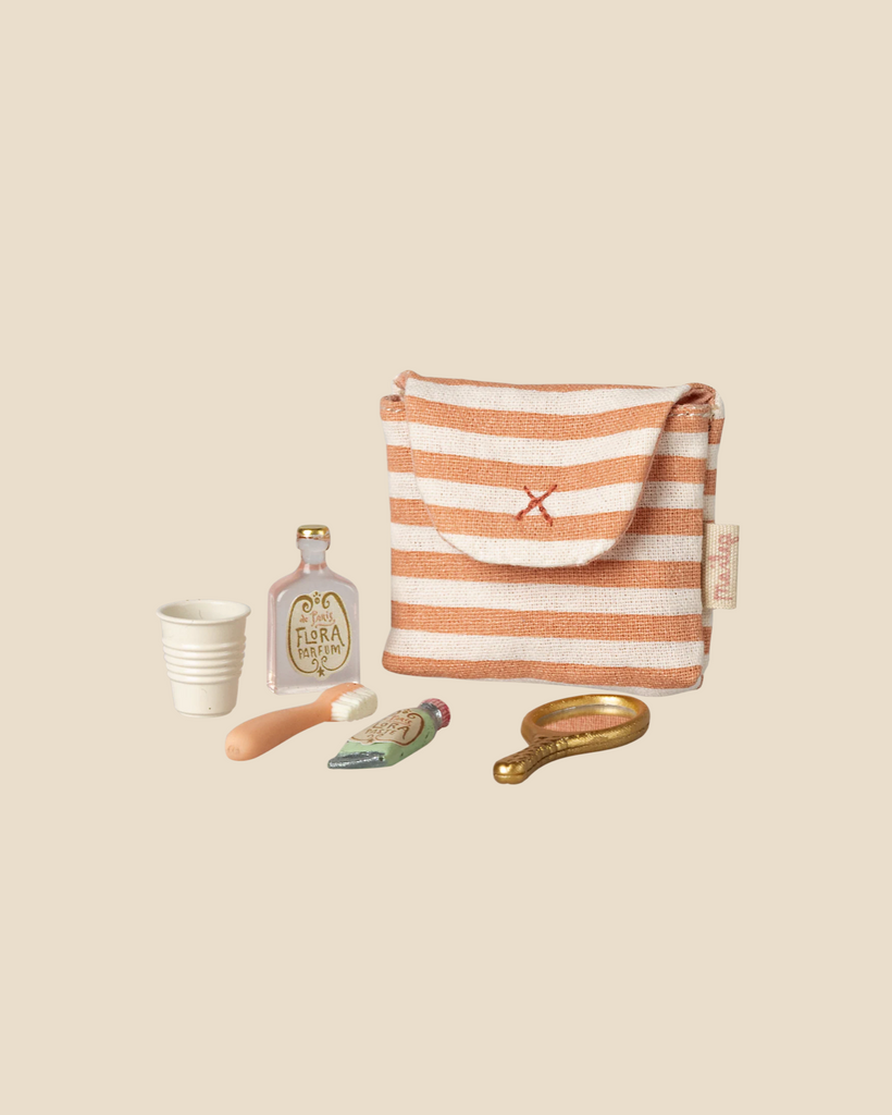 The Maileg Toothbrush Set in Bag, Mouse - Coral Stripe (pre-order, expected 04/15/26) includes a striped pouch, mini cup, "Flora" bottle, tube, spoon, and brass mirror—ideal accessories for mouse family toys or a bedtime playset.