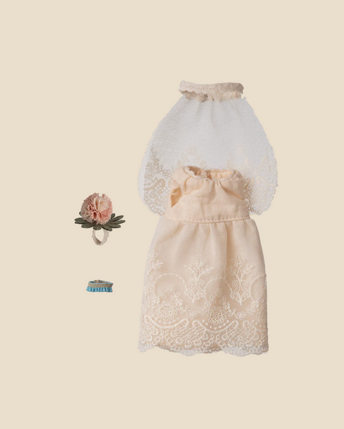 Pre-order: Maileg Wedding Dress, Mum Mouse—features a white lace gown, sheer veil, pink floral hair accessory with green leaves, and a blue ribbon. All items are arranged on a beige background. Expected arrival by 06/15/26.