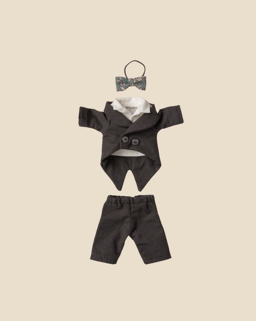The Pre-order: Maileg Wedding Suit, Dad Mouse (Expected arrival by 06/15/26) is a small formal black outfit with jacket, pants, and a floral-patterned bow tie, displayed neatly on a beige background.