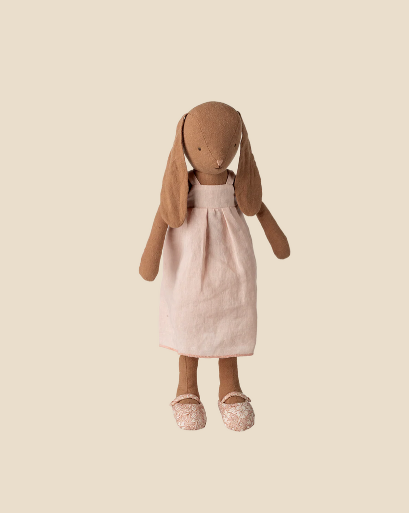 The Pre-order Maileg Bunny Size 3, Chocolate Brown, features soft fur, long floppy ears, a pale pink natural-fabric dress, and sparkly pink shoes. Expected arrival: 02/15/26. Displayed against a plain beige background.