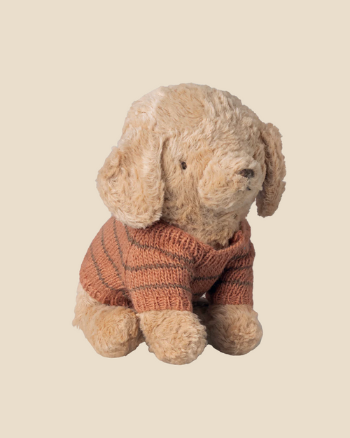 The Pre-order: Maileg Puppy Knitted Sweater - Coral features a soft plush puppy with light brown fur and floppy ears wearing a cozy coral and orange sweater, sitting upright against a plain beige background. Expected arrival: 04/15/26.