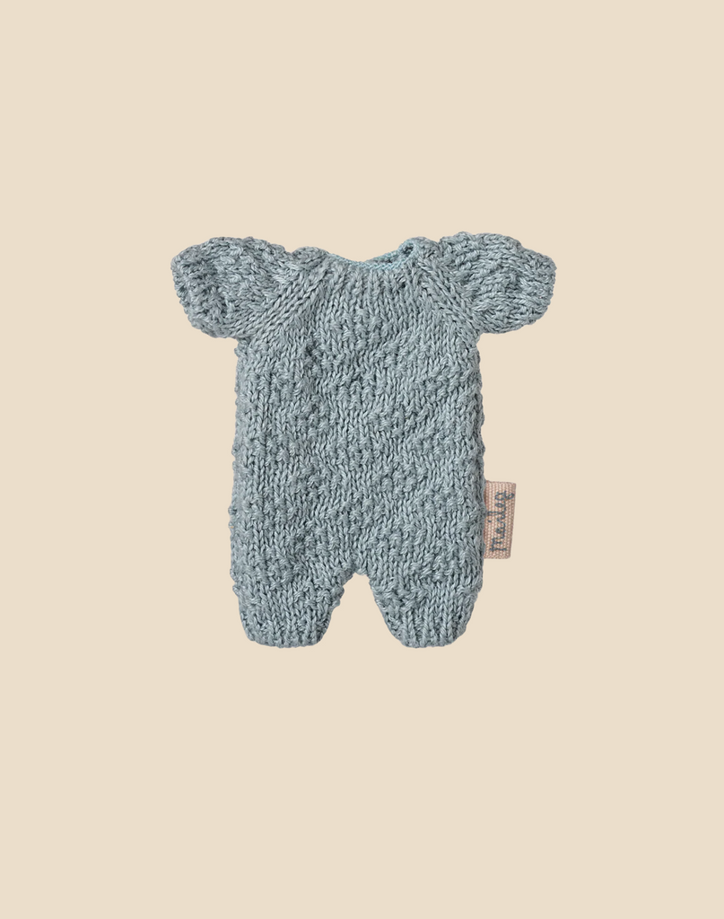 A Maileg Easter Egg with Lamb & Extra Clothing, featuring a small light blue knitted baby romper with short sleeves and legs, textured pattern, and side fabric tag—ideal for dressing up your Micro Lamb.