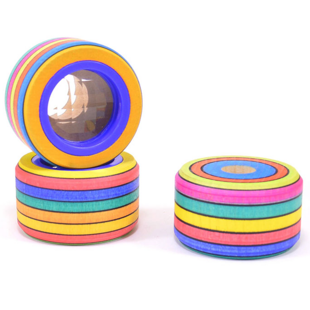 Three stackable, round Mader Wooden Compound Eye Lens toys in maple are shown: one features a compound eye lens, another stands upright, and the last lies flat. Each piece displays bright concentric circles.