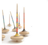 Several tall, colorful spinning tops—including the Mader Arabella Spinning Top in Purple—stand upright on a white surface in a scattered arrangement, some in sharp focus and others blurred, highlighting the toy's safety features.