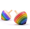 Two Mader Rainbow Egg Spinning Tops in purple are displayed on a white background—one classic Austrian toy with rainbow stripes is in sharp focus, while the other appears slightly blurred behind it.
