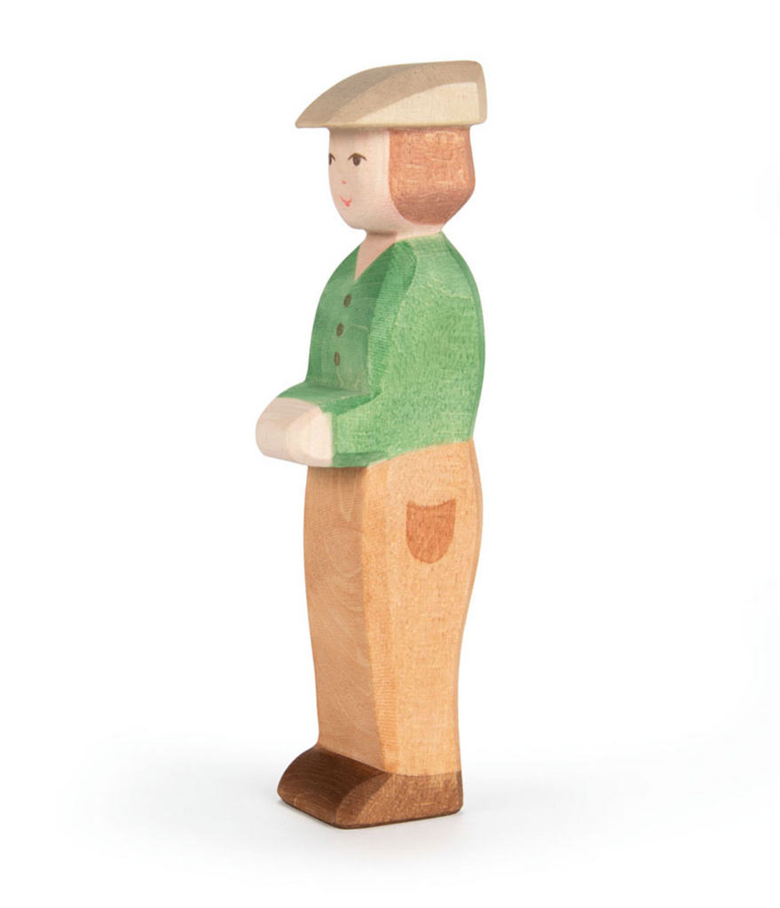 The Ostheimer Young Farmer is a handcrafted wooden toy figure in a green shirt, tan pants, brown shoes, and a beige hat—ideal for imaginative play.