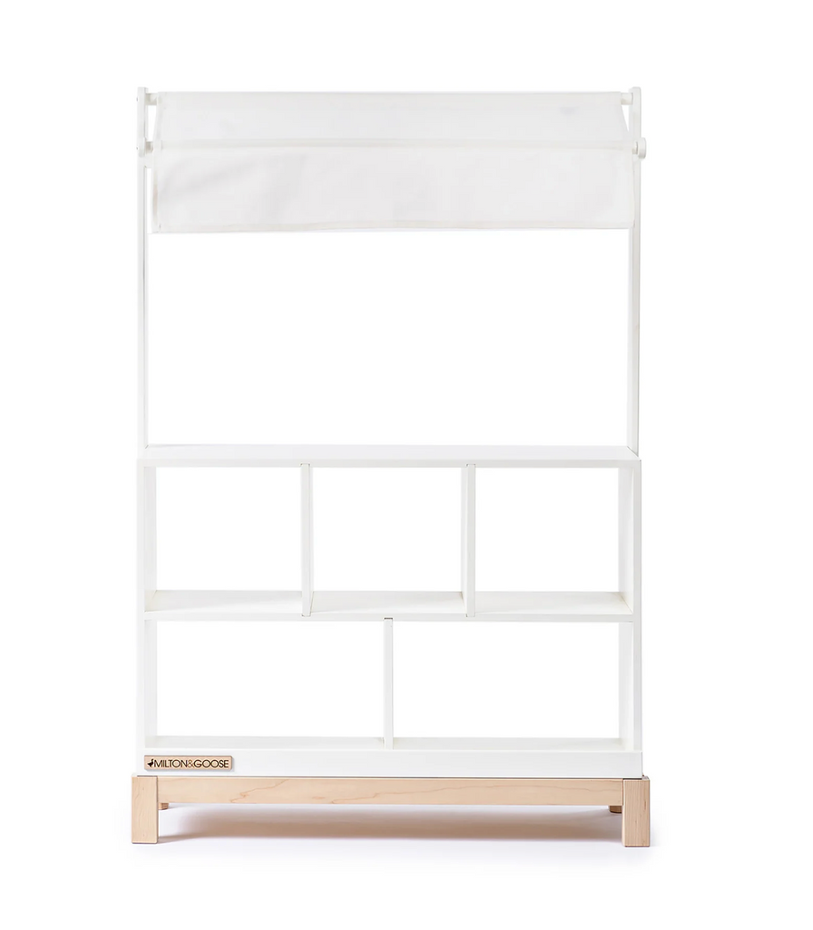 The Milton & Goose Market Stand is an heirloom-quality handcrafted wooden stand with a charming white finish, a canopy, and multiple shelves—perfect for imaginative play and storage.