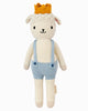 Cuddle + Kind Sebastian the Lamb is a hand-knit doll with a neutral expression, yellow crown, light blue suspenders, and white shorts—crafted with sustainable, fair trade practices.