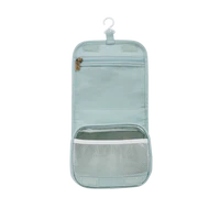 A light blue, Olli Ella See Ya Wash Bag - Steel Blue with a transparent front pocket, partially open, against a white background.