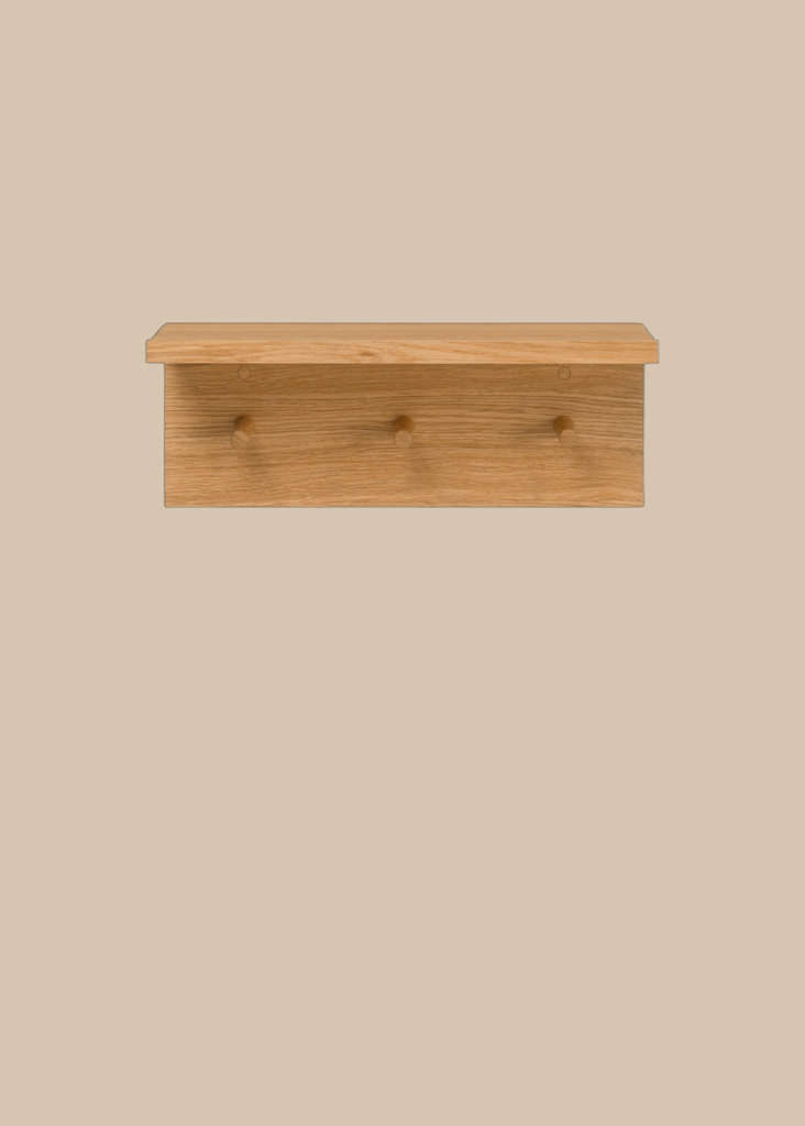 The Ferm Living Place Rack - Small is a simple oak wall rack with three round pegs for hanging items, ideal for home organization, shown mounted on a light beige background.