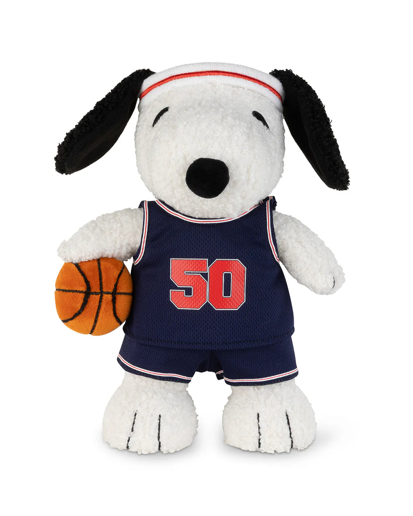 Peanuts Snoopy - Basketball plush features Snoopy in a blue basketball jersey with the number 50, matching shorts, a white headband with a red stripe, and holding an orange basketball under one arm.