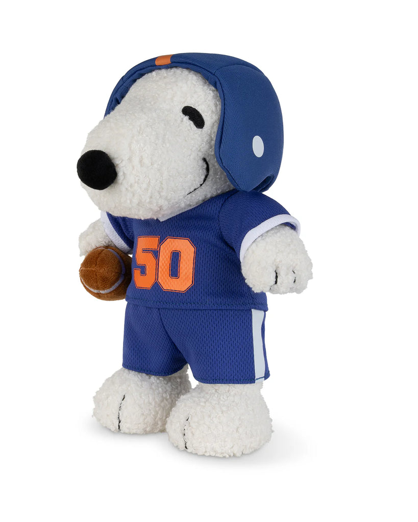 The Peanuts Snoopy - American Football plush by Bon Ton Toys features Snoopy in a blue football uniform with orange number 50, a matching helmet, and holding a small football under one arm.