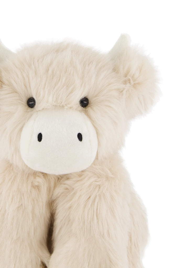 Snuggle Bunnies - Hilda The Highland Cow is a plush toy with fluffy beige fur, round black eyes, small cream-colored horns, and a large cream snout—an adorable cuddle companion against a white background.