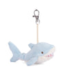 Introducing the Bukowski - Splash Shark Bag Charm: a plush light blue shark keychain featuring a white belly, embroidered eyes, and charming white felt teeth. Attached to a short fabric loop and metal clip, this cuddly accessory makes an adorable bag charm for any ocean lover.