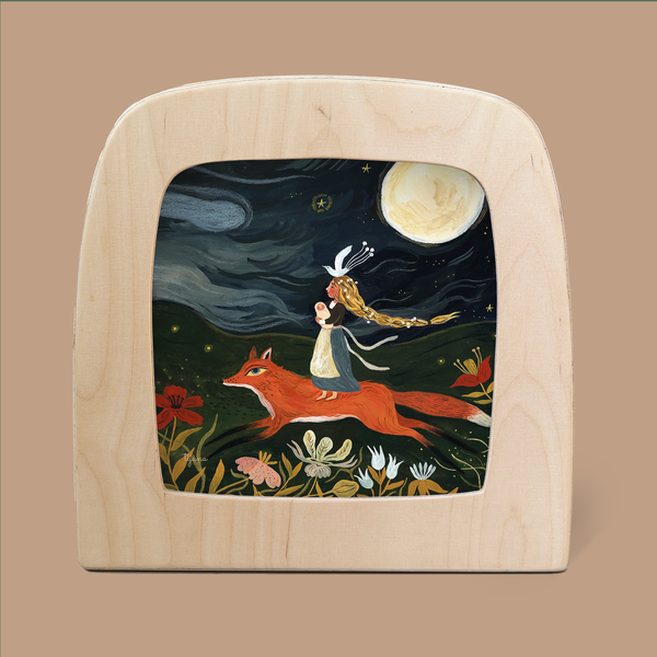 A framed illustration titled "Silhouette Only - Fox Mother Silhouette for Toverlux Lamp" by Tijana Draws depicts a girl with flowing hair and a dress riding on the back of a Fox Mother under a luminous full moon, set against a whimsical landscape of flowers and a starry sky. It's elegantly framed in light-colored wood.