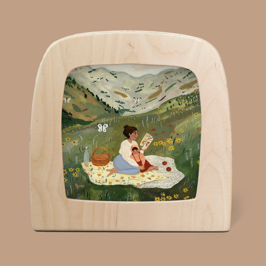 The "Silhouette Only - Picnic Silhouette for Toverlux Lamp" beautifully captures the enchanting scene of a woman reading to a child on a picnic blanket in a meadow, with majestic mountains as the backdrop. Butterflies flutter around a nearby picnic basket, enhancing the charm and tranquility of this captivating silhouette.