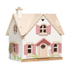 A detailed model of the Cottontail Cottage Dollhouse with a pink door, shutters, and a small porch, featuring decorative elements like a heart, clock, and a bunny figure at the front.