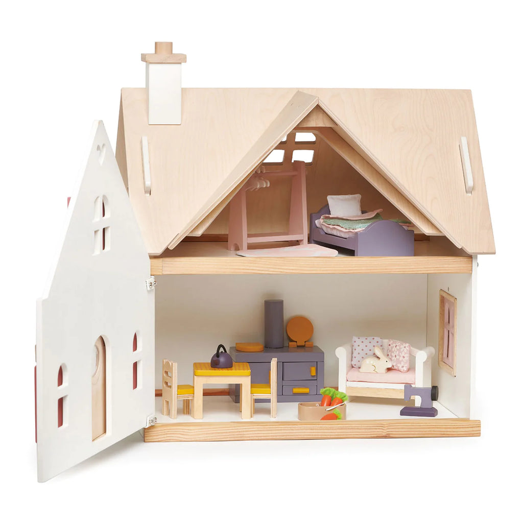 The Cottontail Cottage Dollhouse features an open facade showing two furnished floors, including a bedroom, kitchen, and living area. The house resembles a countryside cottage designed with simplistic details and a natural wood roof.