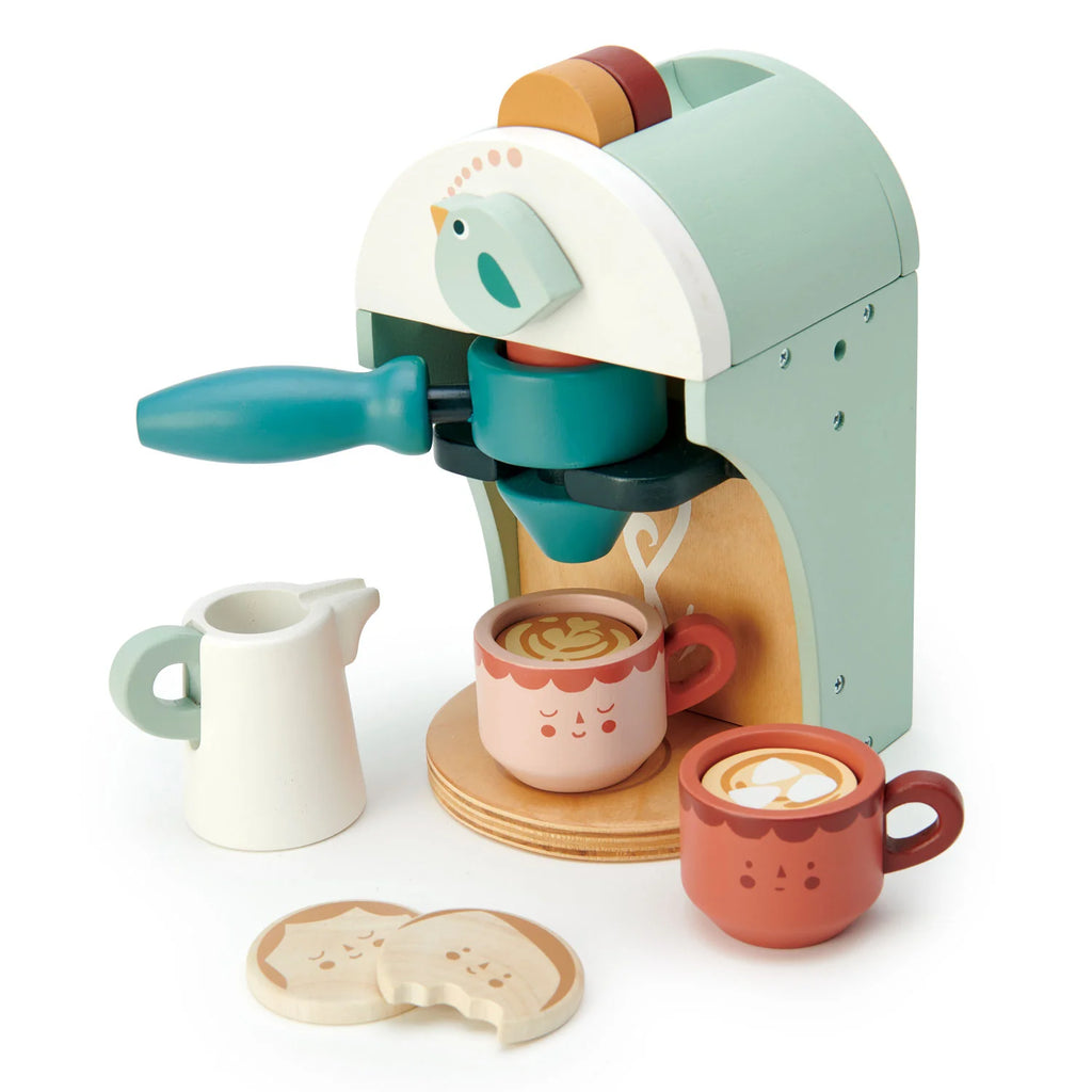 The Babyccino Maker is a pastel wooden toy set featuring two latte art cups, a creamer pitcher, and two bite-marked cookies—perfect for children’s pretend café play.