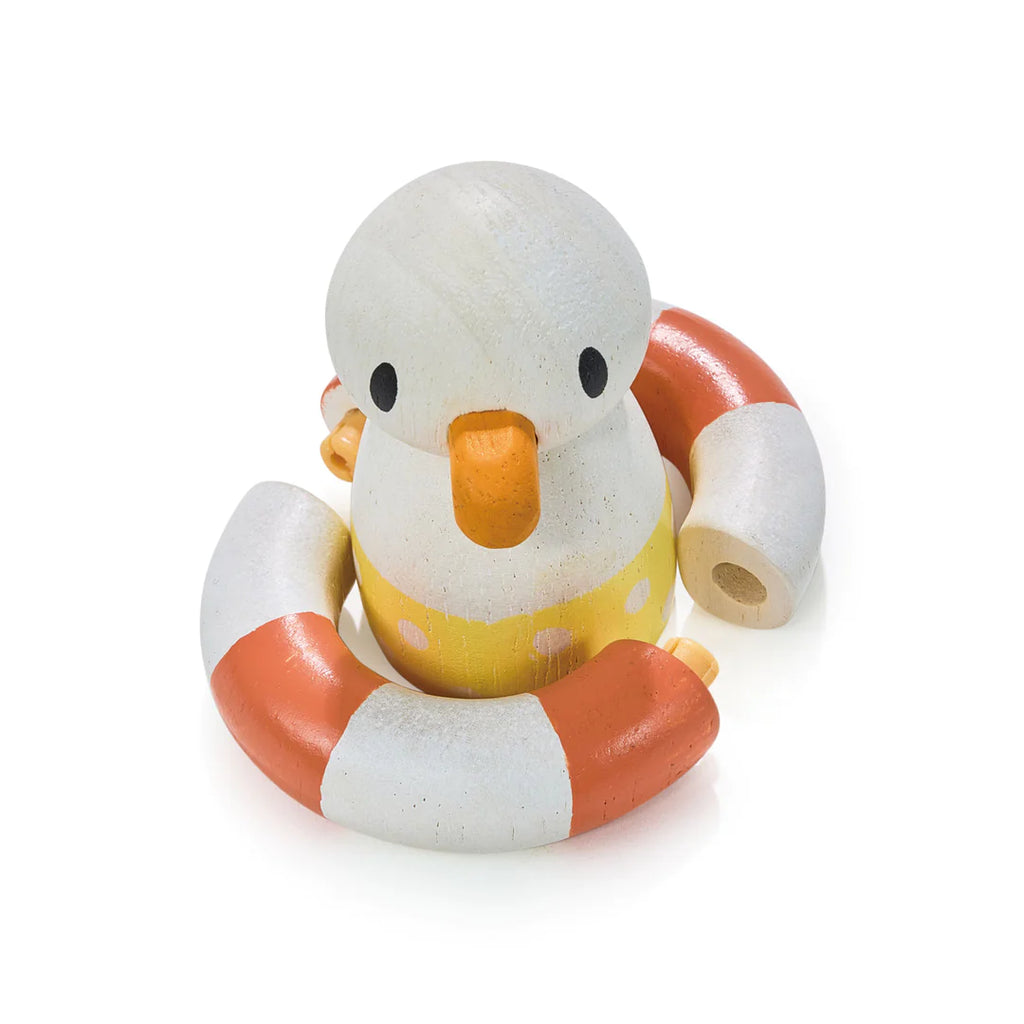 A wooden toy seagull shaped like a duck wearing a yellow swim ring and floating on orange and white Sandy's Beach Hut, isolated on a white background.