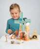 A young girl engaged in imaginative play with a Penny Windmill and other play figures on a table, appearing focused and engrossed.
